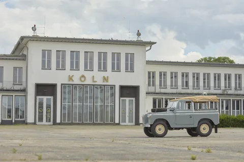 Ein klassischer Land Rover vor einem Gebäude mit Köln-Schriftzug.