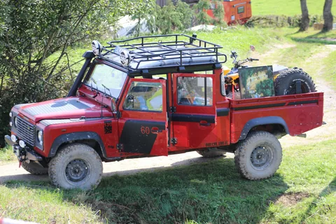 Ein roter Land Rover bei einer Fahrt im Gelände.