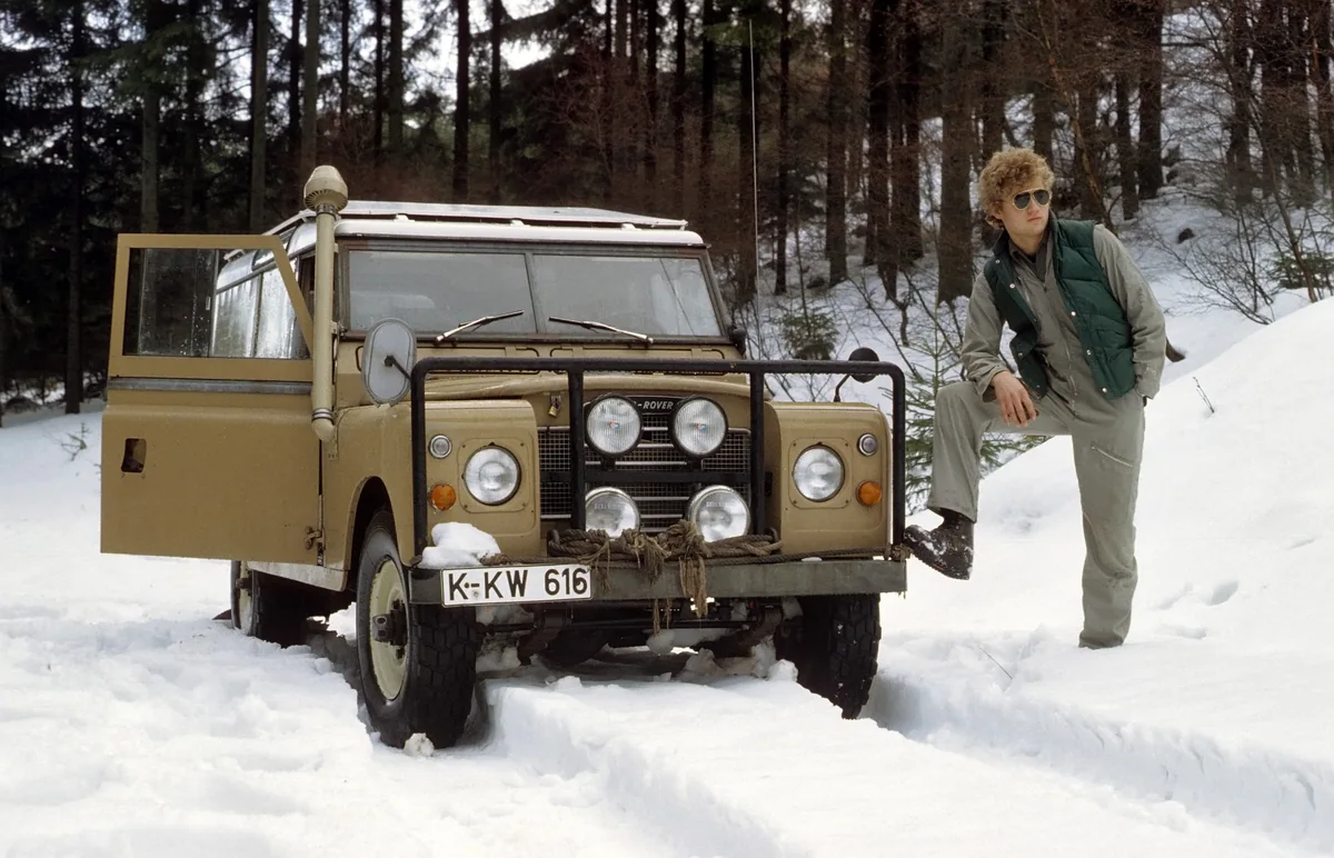 Historische Aufnahme eines Land Rover und eines Mannes im Schnee.